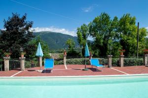 dos sillas azules y sombrillas junto a una piscina en Il Borgo di Mattia, en Cerreto di Spoleto