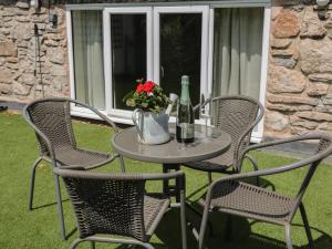 una mesa y sillas con una botella de vino y flores en Wilson Eyre Cottage, en Castleton