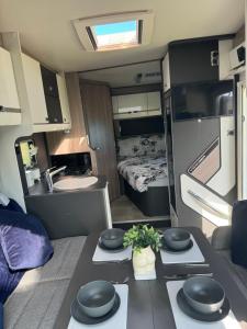 Una sala de estar con una mesa y una cocina en una casa rodante. en Motorhome life, en Radipole