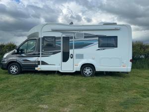 una caravana blanca estacionada en un campo de hierba en Motorhome life, en Radipole