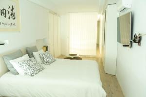 a bedroom with a white bed with pillows on it at OceanSound White in Las Palmas de Gran Canaria