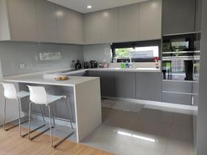 a kitchen with white cabinets and a counter and chairs at Balutinha's house in Barcelos