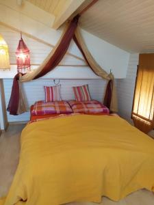 a bedroom with a yellow bed with two red pillows at maison du portail vieil in Vendres
