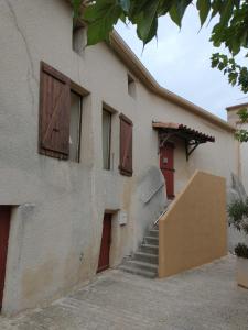 a building with wooden doors and a stairway at maison du portail vieil in Vendres