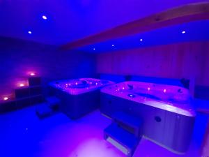 ein Zimmer mit zwei Whirlpools und violetten Lichtern in der Unterkunft Le Zébresse in Combrand