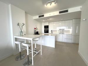 una cocina blanca con encimera blanca y taburetes en Pure South Luxury Apartment, en Manilva 43 fotos más