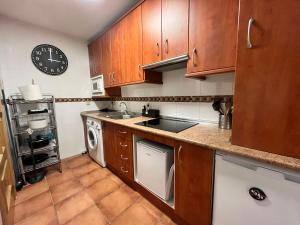 a kitchen with wooden cabinets and a sink and a dishwasher at Apartamento Kariba Antigua Casa Anita in Güéjar-Sierra