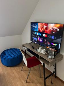Zimmer mit einem Schreibtisch mit einem blauen Ottomanen und einem TV in der Unterkunft Hotell City Karlshamn in Karlshamn
