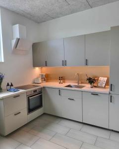 a kitchen with white cabinets and a sink at Modern & Homely Apartment - Free Parking in Viby