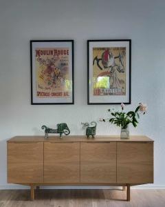a wooden dresser with two framed posters on a wall at Modern & Homely Apartment - Free Parking in Viby +18 photos