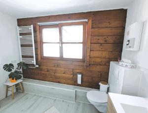 Łazienka z drewnianymi ścianami, toaletą i oknem w obiekcie Apartment Nähe Airbus w mieście Manching