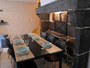 a dining room with a table and a brick fireplace at Au Gré des Saisons - Vulcania & Lemptégy in Pontgibaud +6 photos