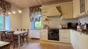 a kitchen with white cabinets and a table with chairs at Pērles in Durbe