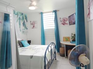 Camera con letto, tavolo e ventilatore. di Chambre d'hôte Kay Arlette - chez l'habitant a Le Robert