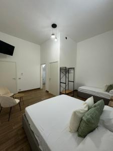 a white bedroom with two beds and a chair at Casa Bedda - INTERA CASA CON 3 CAMERE CON BAGNO PRIVATO, ARIA CONDIZIONATA E NO ZTL/ENTIRE APARTMENT WITH 3 BEDROOMS WITH PRIVATE BATHROOM, AIRCON AND NO LTZ in Castellammare del Golfo