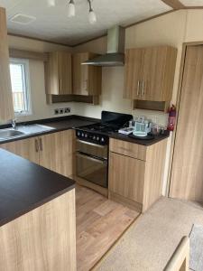 a kitchen with wooden cabinets and a stove top oven at Natland Caravan Park in Kendal