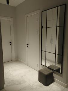 a white room with a large mirror and a stool at Tina's home in Batumi