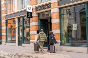 dos personas caminando por una calle con su equipaje en K7 Hotel Oslo, en Oslo