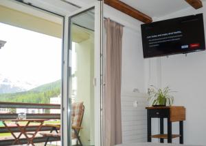 a room with a tv and a balcony at swissme - modernes Studio mit Balkon & Parkplatz & Netflix in St. Moritz