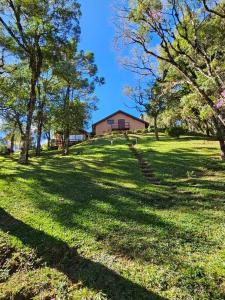 a grassy field with a house in the background at Lareira forno e fogao a lenha nas montanhas in Camanducaia