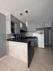 Il comprend une cuisine équipée d'un comptoir noir et d'un réfrigérateur. dans l'établissement Flat Cactos, à Surubim