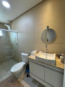 une salle de bains avec toilettes, lavabo et miroir dans l'établissement Flat Cactos, à Surubim