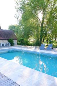 a swimming pool with two chairs in a yard at Moulin de Petoulle in Charenton sur Cher
