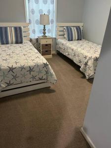 a bedroom with two beds and a table with a lamp at Fernandina Executive Retreat in Fernandina Beach