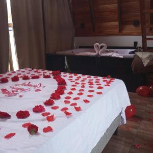 a large white cake with red roses on a bed at Pousada Sestrem - São João Batista - SC in São João Batista