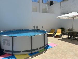 a hot tub in a patio with chairs and an umbrella at Piscina en Herrería 18 in Conil de la Frontera