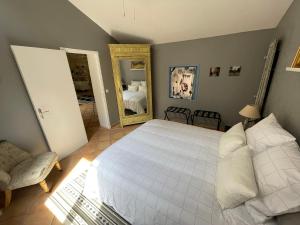 a bedroom with a white bed and a mirror at La Porte Rouge in Pézenas