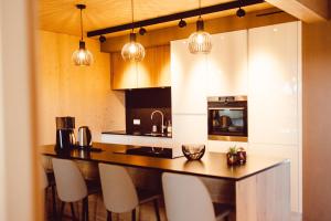 TarchampsFerienhaus Gîte Al Scheier Tarchamps的厨房配有吧台，配有白色椅子和吊灯