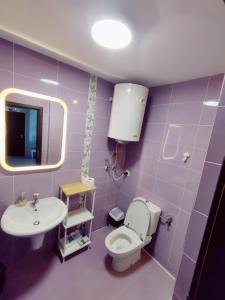 a purple bathroom with a toilet and a sink at Neptun Blue Apartament in Neptun