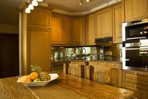 a kitchen with wooden cabinets and a bowl of fruit on a table at Residenz Ambassador A22 in Leukerbad