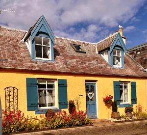 a yellow and blue house with blue shutters at Romantic luxury Cottage right next to the ocean in Saint Abbs