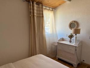 - une chambre avec un lit, un miroir et une commode dans l'établissement Maisonnette - Résidence Malamousque, à Aigues-Mortes