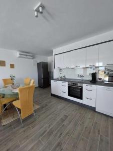 a kitchen with white cabinets and a table and chairs at Apartments Mišković in Vir