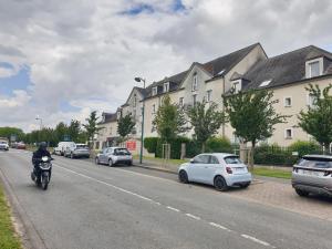 un hombre en una motocicleta por una calle con coches en DiscoveryHome 4Pers Disneyland Paris à 10 min bus, Free Parking, Outlet Shopping, Village Nature, en Magny-le-Hongre