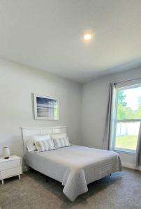 Un dormitorio blanco con una cama y una ventana. en Palm Coast 3br 2ba beach home, en Palm Coast
