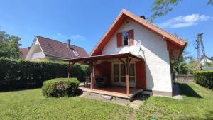 a small house with a porch on a lawn at HauSol Vendégház in Gárdony
