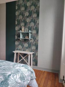 a bedroom with a green wall with a bed and a table at charmante chambre chez l'habitant in Montfort-le-Gesnois