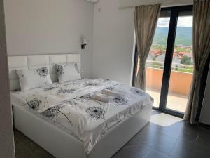 a white bed in a room with a large window at Hotel Albatros in Prizren