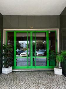 a green door of a building with two potted plants at Casinha das Memórias in Vieira de Leiria
