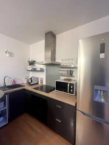 a kitchen with a stainless steel refrigerator and a sink at WonderSuite appartement - centre ville avec parking couvert -15mn de Paris et 10 mn de Stade de France, wifi, Netflix in Deuil-la-Barre