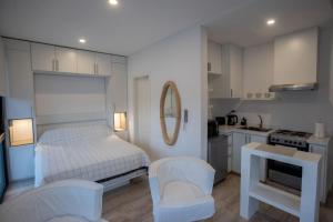 a white bedroom with a bed and a kitchen at Increíble estudio en el centro in San Pedro