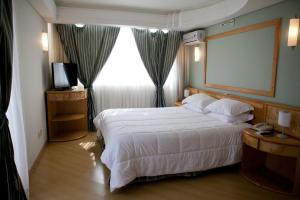 a hotel room with a bed and a large window at Atalaia Palace Hotel in Guarapuava