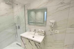 a white bathroom with a sink and a shower at Beautiful & luxurious apartment in Vlorë