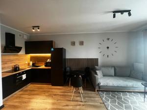 a living room with a couch and a clock on the wall at Apartament Blisko Centrum in Suwałki