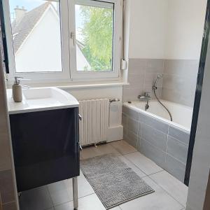 ein Badezimmer mit Waschbecken, Badewanne und Fenster in der Unterkunft La maison d'à côté in Montreuil-sur-Mer