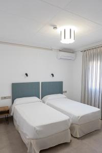 deux lits dans une chambre aux murs blancs dans l'établissement Venta de Terreros, à San Juan de los Terreros